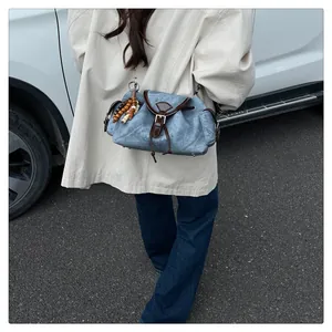 Détail d'un sac bandoulière en denim bleu avec lanières en cuir marron et perles en bois