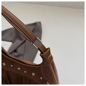 Gros plan du sac seau en cuir marron avec des franges et des rivets en étoile