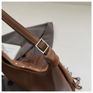 Détail du sac seau vintage en cuir marron avec clous argentés et franges à glands