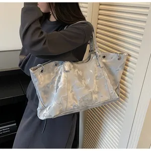 Λεπτομερής όψη ασημί μεταλλικής τσάντας tote με vintage υφή και μεταλλικούς κρίκους