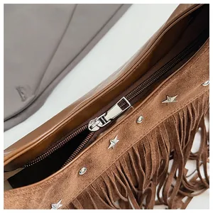 Détail du sac seau en daim marron avec rivets en étoile et franges suspendues