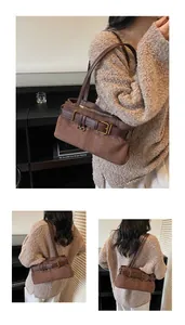 Detail view of brown suede underarm bag featuring a vintage metal belt buckle accent
