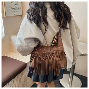 Détail du sac seau en daim marron avec franges et rivets en forme d'étoile argentée