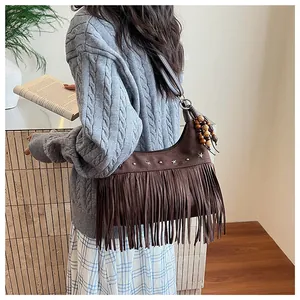 Détail du sac seau en daim marron avec franges, clous étoiles et perles en bois