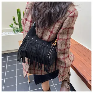 Vue de dos d'un modèle portant un sac seau vintage en daim noir avec franges et clous