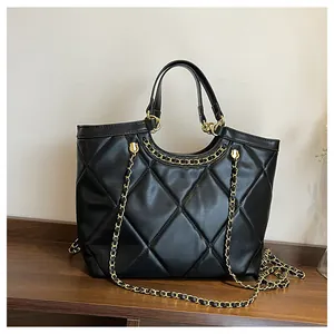 Détail d'un sac cabas noir matelassé avec chaîne dorée et texture cuir lisse élégante