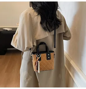 Brown quilted mini bucket bag worn crossbody over a light brown trench coat for women