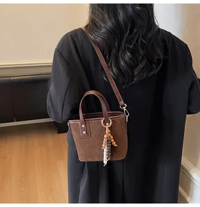 Detail of vintage dark brown suede bucket bag with quilted patterns and bead charm