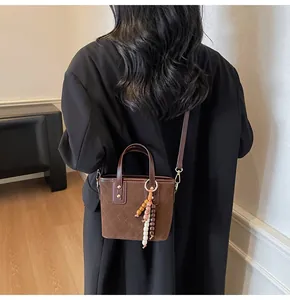 Close-up of brown quilted bucket bag with colorful bead charm on a mannequin