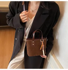 Detail view of brown quilted suede bucket bag with beaded charm and shoulder strap