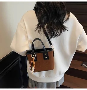 Detail view of brown quilted suede bucket bag with wooden beads on model in hallway