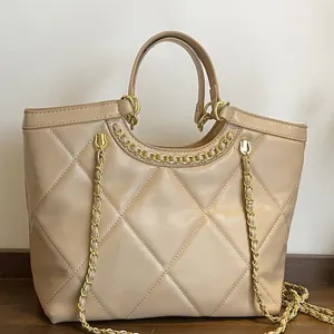 Sac cabas beige matelassé avec motif losanges et chaîne dorée sur surface en bois