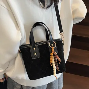 Retro black quilted suede bucket bag with decorative wooden beads on a staircase