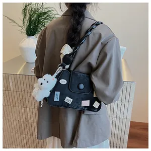 Detalle de bolso de hombro en ante negro con parches bordados y un colgante de perro suave