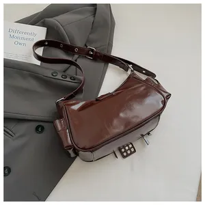Close-up of a dark brown glossy biker shoulder bag featuring side zip pockets and rivets