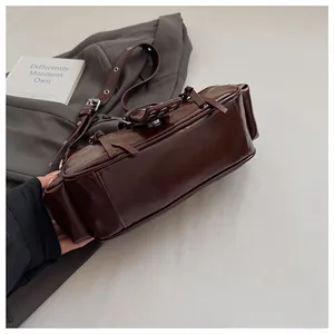 Detailed view of dark brown glossy PU leather texture and metal buckle on shoulder bag