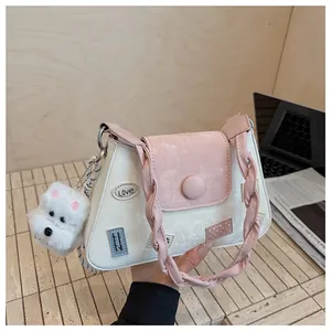 Detalle del bolso bandolera moderno con asa tejida y amuleto de perro de peluche blanco