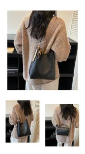 Détail d'un sac seau noir et d'un petit sac bandoulière avec pompon en perles coloré