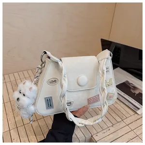 Bolso trapecio blanco con parches, asa trenzada y colgante de perro de peluche suave