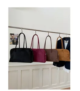Fila de bolsos de terciopelo en negro, granate, café y caramelo en un soporte de metal