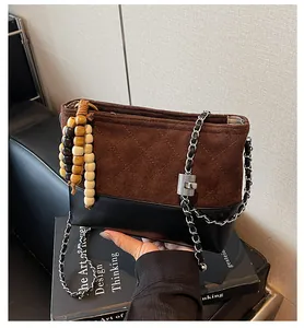 Détail du sac matelassé en daim et cuir avec breloque en perles de bois et chaîne argentée
