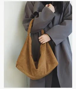 Detail of the caramel brown suede hobo bag with a decorative knotted handle design