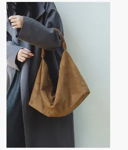 Detail of dark caramel suede hobo bag featuring a unique knotted strap design on shoulder
