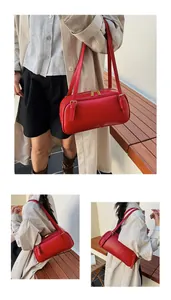 Detalle de bolso Boston en cuero rojo con correas ajustables y cremalleras de metal dorado