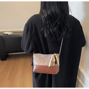 Modèle portant un sac matelassé vintage en cuir marron sur un blazer noir chic