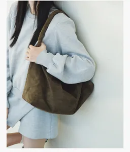 Detail of a brown suede hobo bag featuring a knotted shoulder strap and soft texture