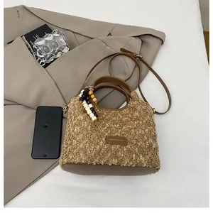 Dettaglio della borsa a tracolla in peluche con logo in pelle e ciondolo con perle in legno