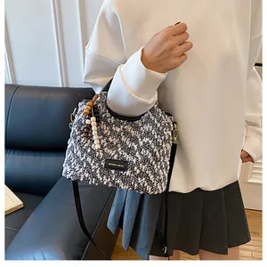 Dettaglio borsa a tracolla in tweed con manico in pelle e ciondolo decorativo con perline