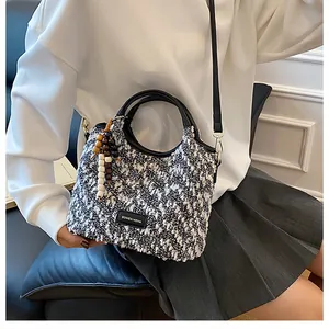 Dettaglio della trama in tweed bianco e nero e del logo in pelle sulla borsa