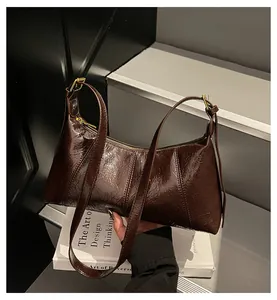 Λεπτομέρεια από το σκούρο καφέ δέρμα με υφή κεριού και χρυσά στοιχεία στην τσάντα