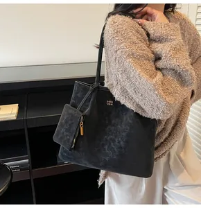 Detail of black large tote bag with gold branding and matching small zipper pouch