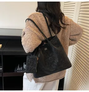 Black matte leather tote bag detail with detachable coin purse and white text logo