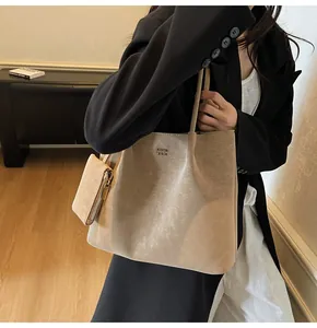 Detail view of large beige tote bag with metallic logo and matching coin purse charm