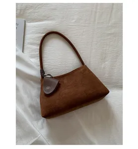 Macro detail of brown suede underarm bag showing fine matte texture and knotted handle