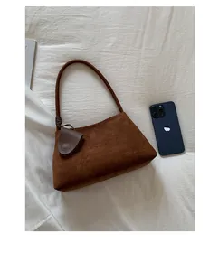 Deep brown suede shoulder bag detail shown next to a smartphone for size comparison