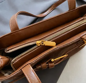 Détail de la fermeture éclair dorée et de la doublure rayée du sac à main en daim marron