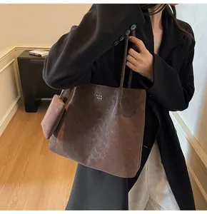 Close-up of a large dark brown tote bag set with metal logo and matching coin purse