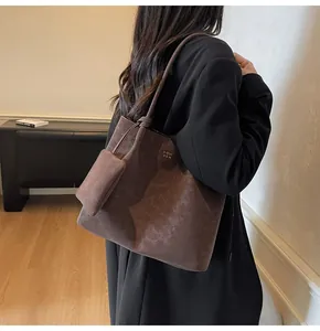 Detail of a large dark brown suede tote bag with a small matching pouch accessory on a shoulder