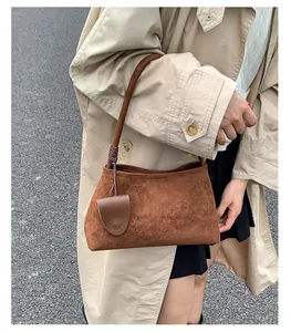 Detail view of brown matte suede shoulder bag with decorative dark woven knot