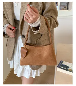 Detail of vintage brown suede shoulder bag showing matte texture and matching charm