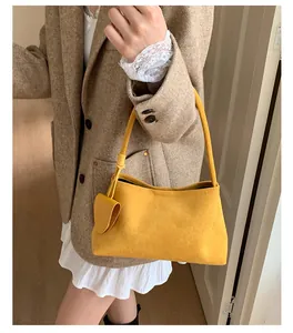 Detail of ginger suede shoulder bag with knotted strap and heart-shaped pendant