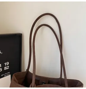 Detail of dark brown tote bag showing slim leather straps and magnetic snap closure