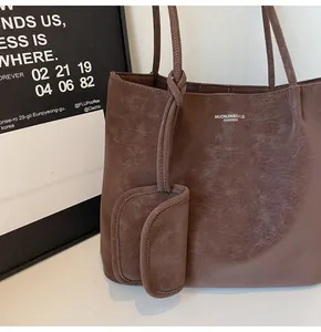 Detail of a brown tote bag showing its vintage leather texture and matching sub-pouch