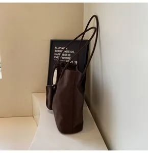 Detail of a dark brown vintage faux leather tote bag with matching storage pouch