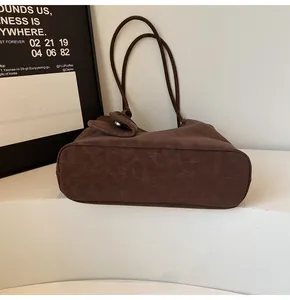 Detail of dark brown tote bag showing matte vintage texture and silver buckle accents
