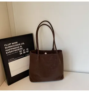 Detailed view of dark brown suede tote bag with slim straps and silver magnetic closure
